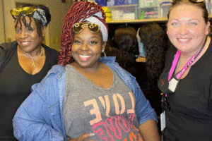Destinee Steele (center) is a JEDI trainer. 2 Black women smiling and 1 white woman smiling