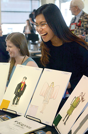 A Thespian smiles as she shows off renderings of original costume designs during the college technical auditions at the International Thespian Festival. 