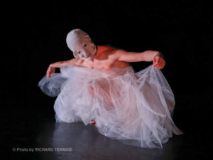 white dancer with white cloth mask covering entire head with sheer dress