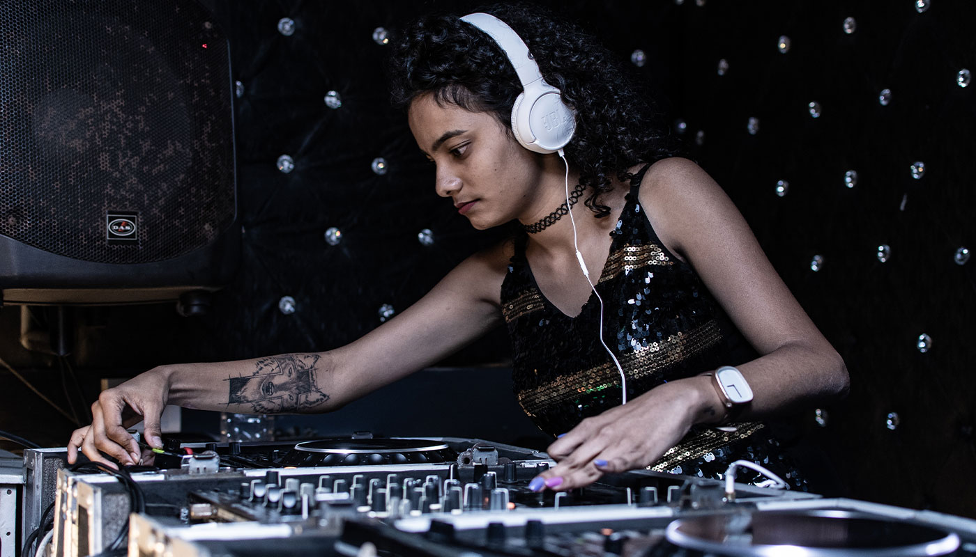 Female at sound board in a black tank top and black background