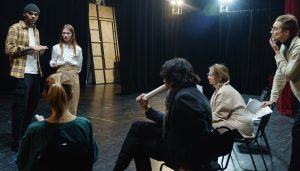adults on a stage talking with scripts in hands