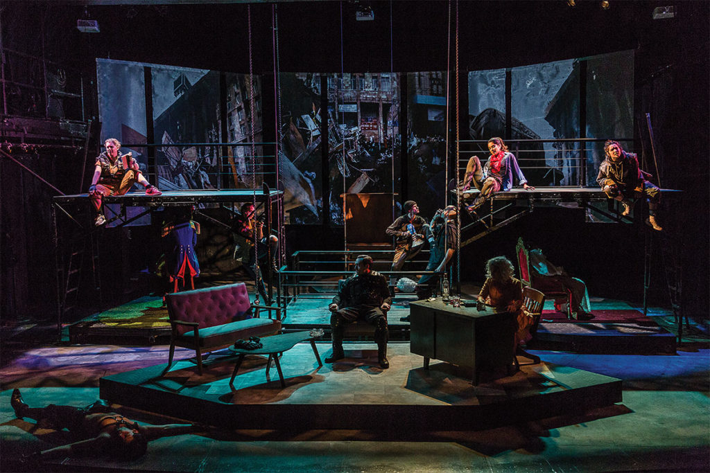 greenish stage lighting with multiple actors in costumes