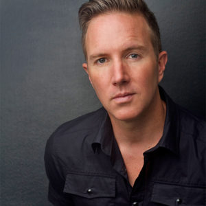 White man in black shirt with black background