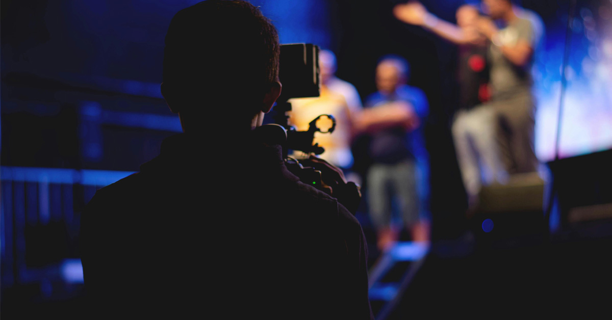 A student filming people on stage