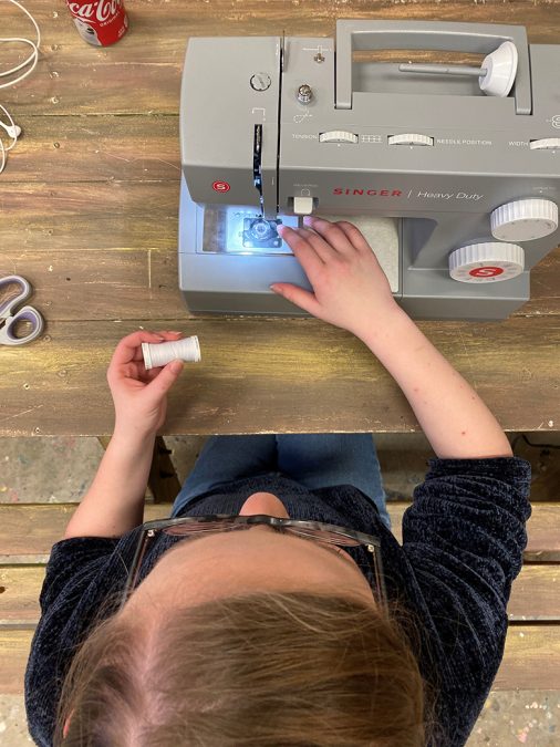 A Thespian threads a sewing machine.