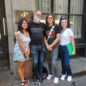 students with adult in front of building