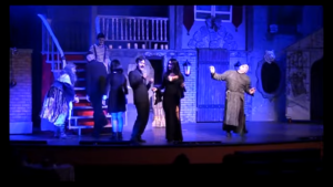 blue light background with Morticia and her husband and Uncle Fester